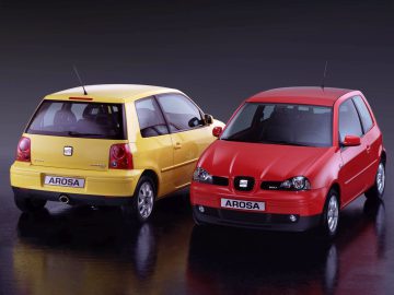 Er worden twee compacte SEAT Arosa-auto's getoond, één geel van achteren en één rood van voren, op een zwarte achtergrond. Alles wat je moet weten – SEAT Arosa Alles wat je moet weten.