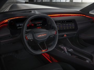 Interieur van de Dodge Charger Daytona SRT met een stuur met ingebouwde bedieningselementen, een digitaal dashboard en een centraal touchscreen-display, allemaal verlicht door rode sfeerverlichting.