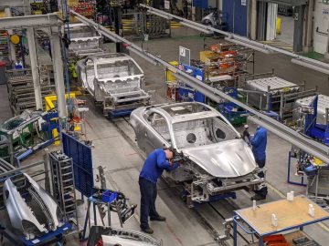 In een Alpine-fabriek zoemt de lopende band van efficiëntie terwijl de arbeiders autoframes in elkaar zetten, omringd door gereedschap en apparatuur.