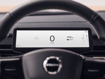 Close-up van het digitale dashboarddisplay van een Volvo EX90 met een snelheid van 0 km/u, een bereik van 488 km en een batterijniveau van 90%. Het stuur met het Volvo-logo is gedeeltelijk zichtbaar.