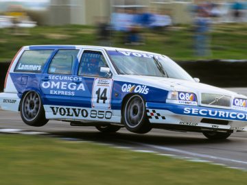 Een Volvo 850 racewagen met nummer 14, versierd met diverse sponsorlogo's, lopend over de baan, gedeeltelijk met hoge snelheid van de grond getild.