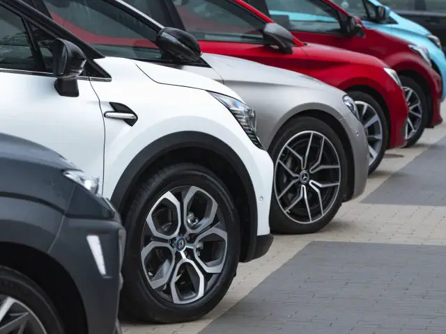 Een rij auto's in diverse kleuren, waaronder enkele van de waardevolste automerken, naast elkaar geparkeerd op een verhard terrein, met de nadruk op de voorwielen en spatborden.