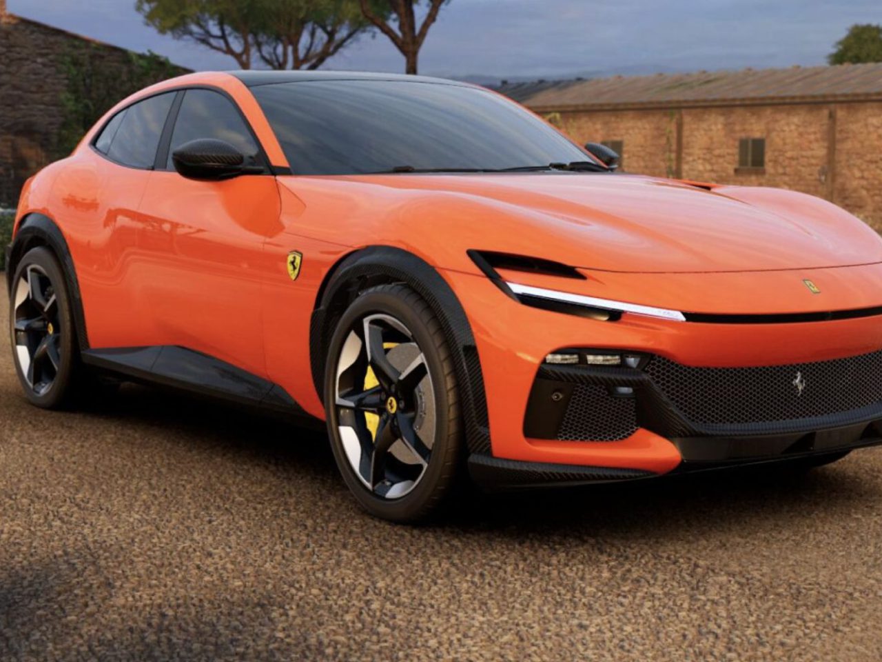 Een oranje Ferrari Purosangue met een strak design staat geparkeerd op een grindoppervlak bij een rustiek gebouw, met bomen op de achtergrond.