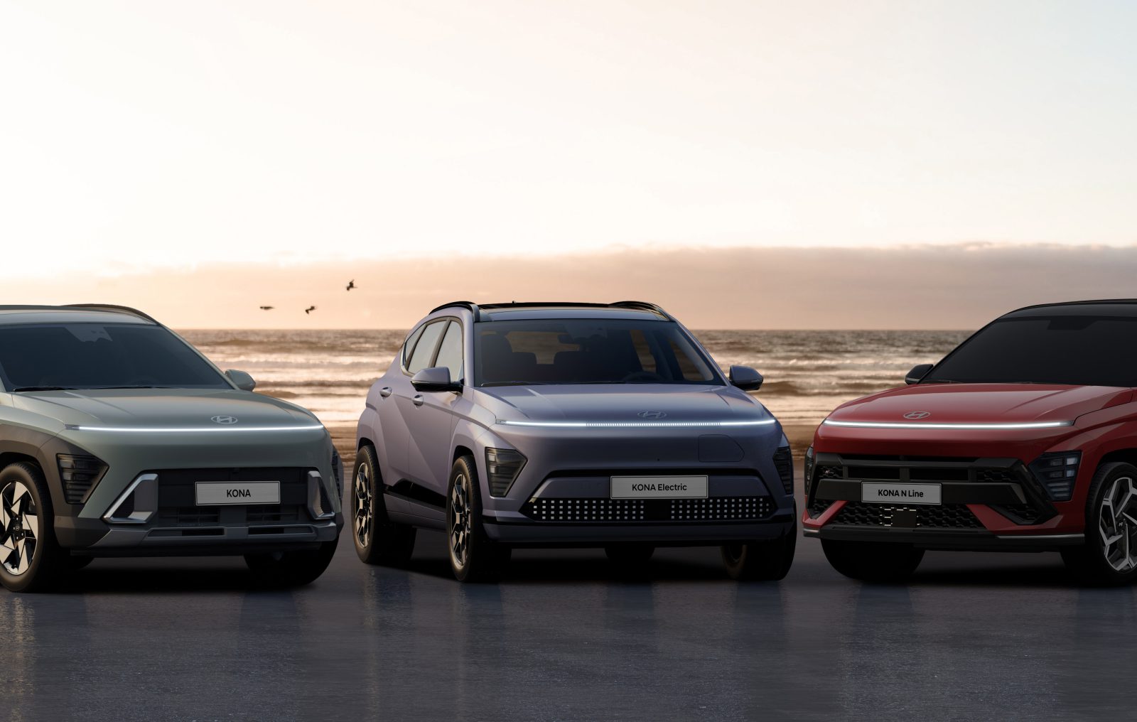 Drie moderne Hyundai Kona-auto's worden bij zonsondergang op een pittoresk strand tentoongesteld.