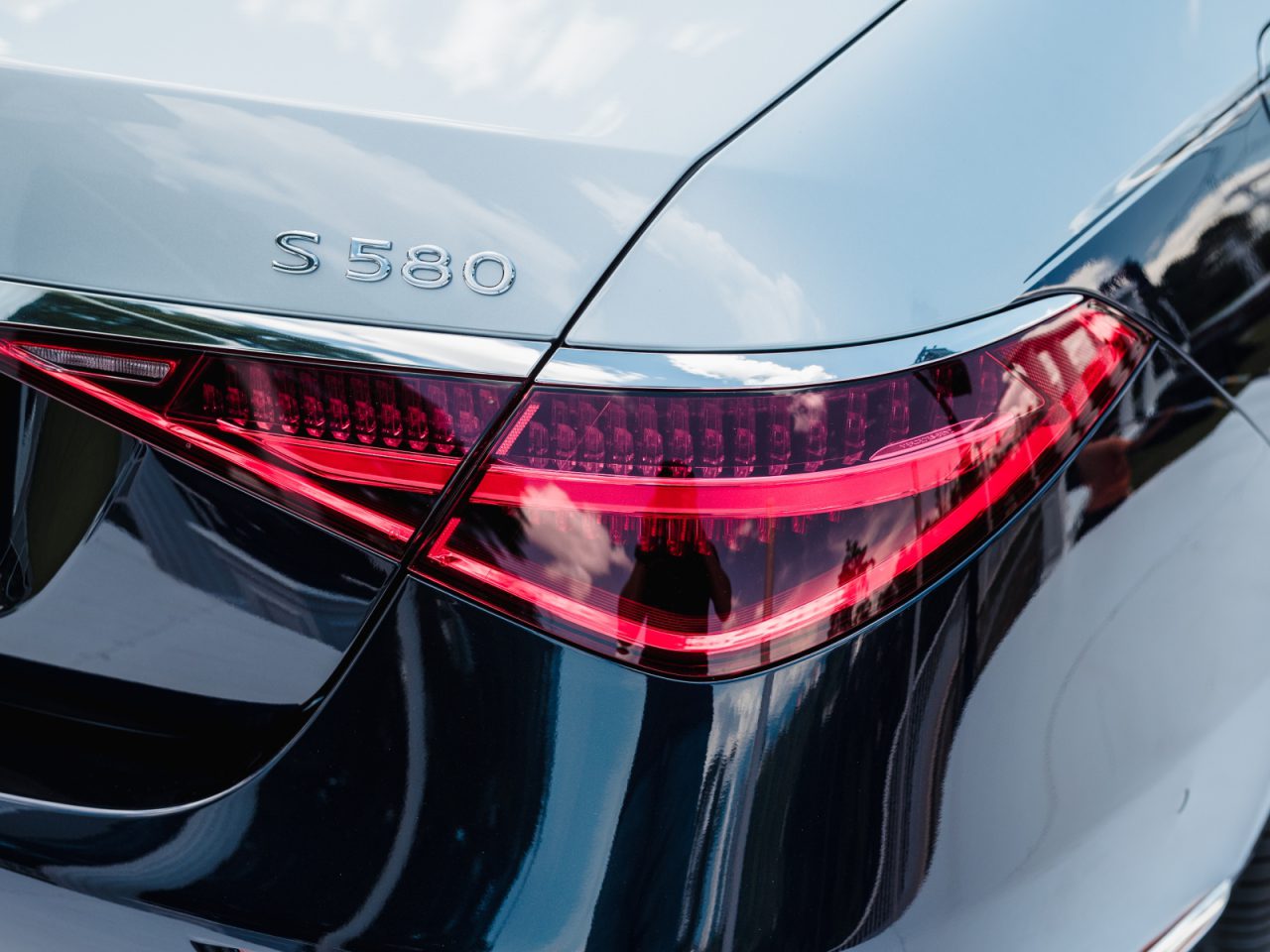 Close-up van het achterlicht en de badges van een zilverkleurige Mercedes-Benz S580 sedan die buiten geparkeerd staat, met uitstekende lakbescherming voor je auto.