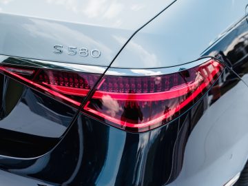 Close-up van het achterlicht en de badges van een zilverkleurige Mercedes-Benz S580 sedan die buiten geparkeerd staat, met uitstekende lakbescherming voor je auto.