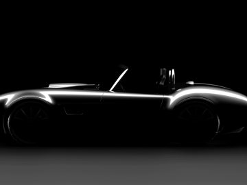 Een zwart-wit silhouet van een AC Cobra 2023 converteerbare sportwagen met een laag profiel, dat de strakke rondingen en het aerodynamische ontwerp in een donkere omgeving benadrukt.