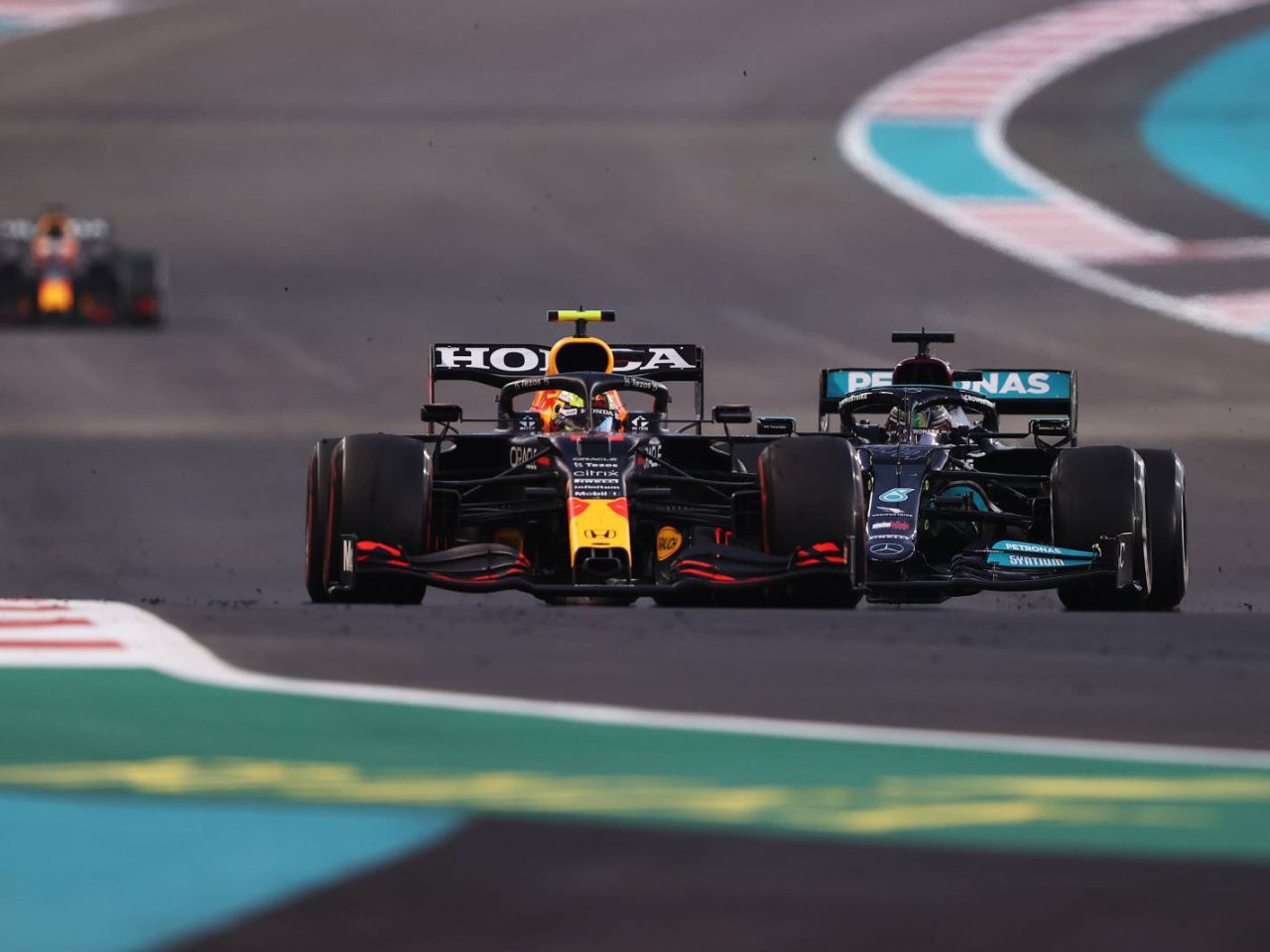 Twee Formule 1-auto's van verschillende teams racen zij aan zij op het circuit van Abu Dhabi, met in de verte een andere auto achter hen aan.