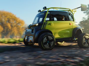 Een kleine, groene Opel Rocks e-xtreme met grote banden rijdt over een onverharde weg in een schilderachtige buitenomgeving met bomen op de achtergrond.