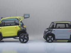 Twee compacte conceptauto's met grote wielen en moderne designkenmerken, de ene geel en zwart met sportaccessoires en de andere zilver en zwart met een strak uiterlijk dat lijkt op een Opel Rocks e-xtreme, worden tentoongesteld in een studio.