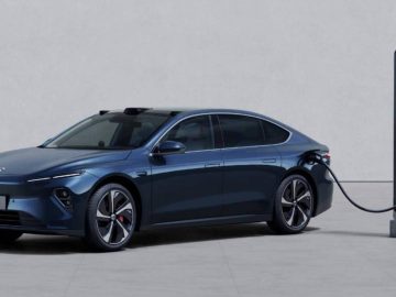 Een blauwe elektrische sedan Nio wordt geparkeerd en aangesloten op een laadstation in een minimalistische setting.