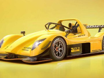 Een felgele Radical SR3 XXR-raceauto staat geparkeerd tegen een gele achtergrond met kleurverloop, waardoor de aerodynamische carrosserie, zijvleugel en gedetailleerde wielen goed tot hun recht komen.