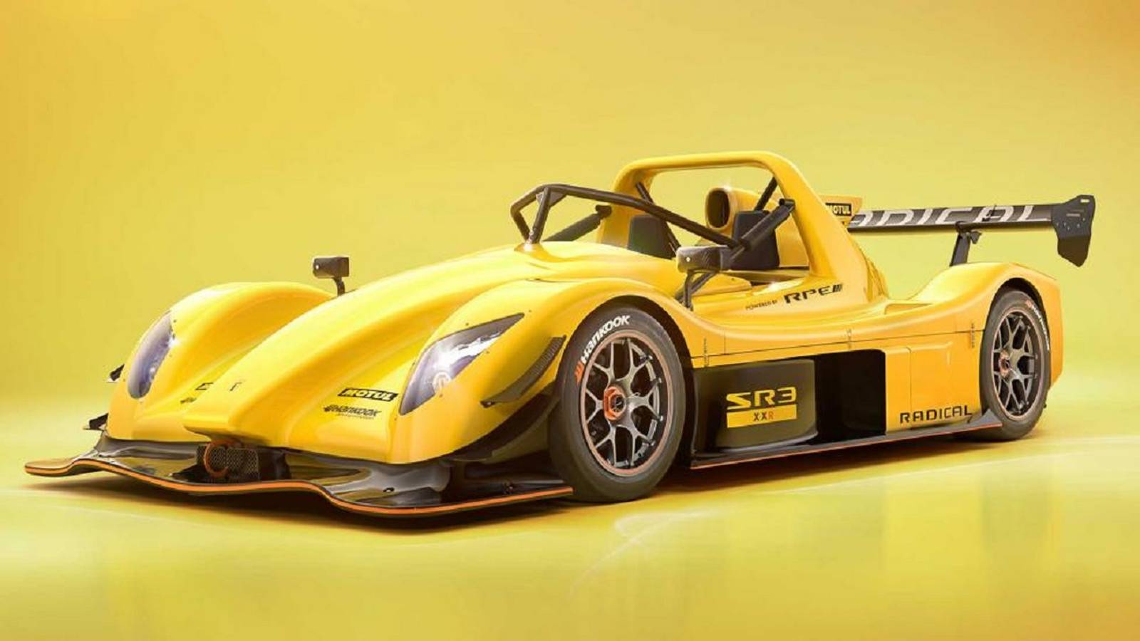 Een felgele Radical SR3 XXR-raceauto staat geparkeerd tegen een gele achtergrond met kleurverloop, waardoor de aerodynamische carrosserie, zijvleugel en gedetailleerde wielen goed tot hun recht komen.