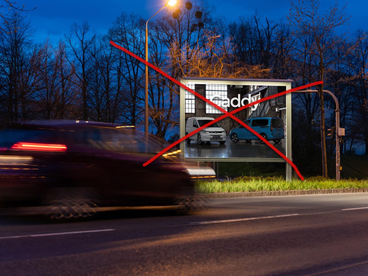 Een reclamebord met "maddrix" en afbeeldingen van busjes zijn rood doorgestreept, 's avonds gezien vanaf een straat met een wazige auto die voorbijrijdt. Bomen en straatverlichting staan op de achtergrond, wat mogelijk een reclameverbod suggereert.