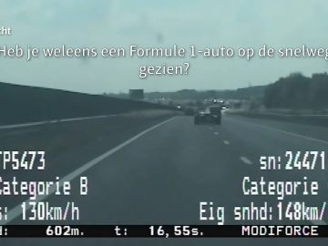 Een F1-auto die over de snelweg raast, met details over snelheid en voertuigcategorie op het scherm. Op het display staat ook een tekst in het Nederlands met de vraag of je ooit een F1-auto op de snelweg hebt gezien.