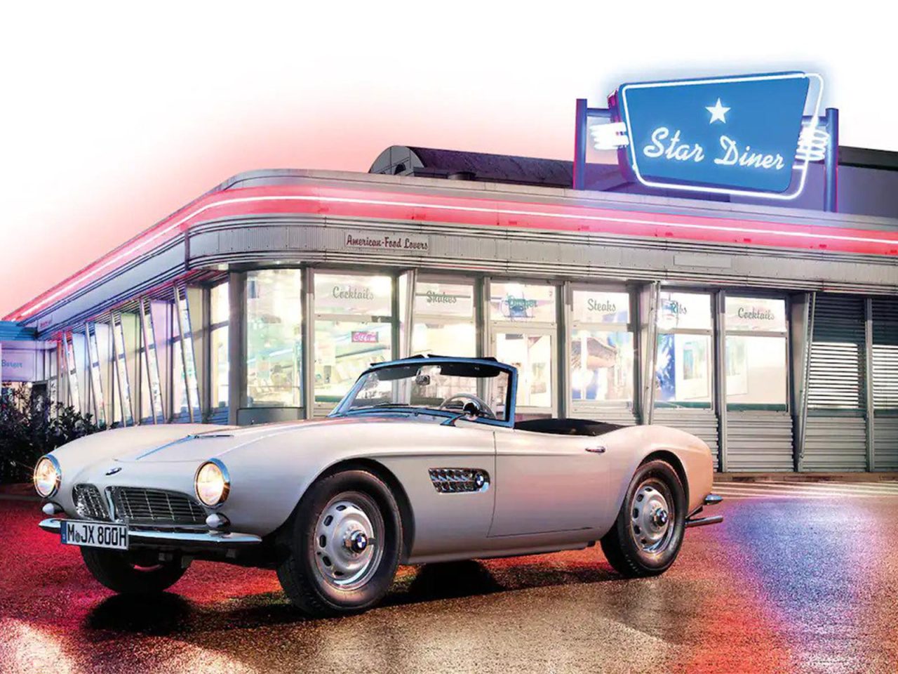 Een klassieke witte BMW 507 cabriolet staat geparkeerd voor een restaurant in retrostijl met een neonbord "Star Diner" in de schemering.