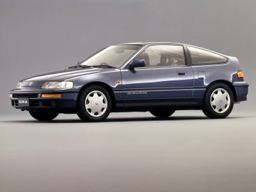 Een blauwe Honda CRX hatchback uit de jaren 80, gezien vanuit een hoek vanaf de linkerkant tegen een neutrale achtergrond.