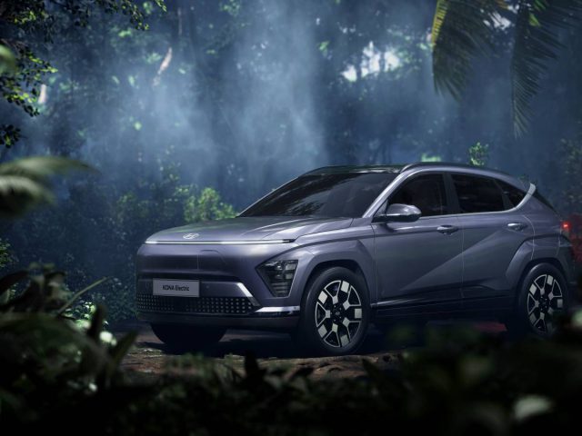 Een zilverkleurige Hyundai Kona-crossover staat geparkeerd in een mistig, bosrijk gebied met dicht gebladerte en diffuus licht dat door de bomen filtert.
