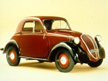 Een vintage Topolino, kastanjebruine en zwarte tweedeurs auto met rode wieldoppen en chromen accenten, weergegeven op een effen achtergrond.