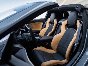 Binnenaanzicht van de luxe sportwagen Corvette E-Ray met tweekleurige lederen stoelen in zwart en bruin, een modern stuur en een middenconsole.