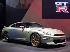 Een zilveren Nissan GT-R 2023-sportwagen wordt tentoongesteld op de vloer van een showroom met een