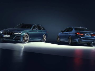 Twee donkergekleurde luxeauto's, een sedan en een stationwagen, tentoongesteld onder studioverlichting op een donkere achtergrond. Beide voertuigen hebben een sportief ontwerp en stijlvolle velgen, die het uitgesproken vakmanschap van Alpina belichamen.