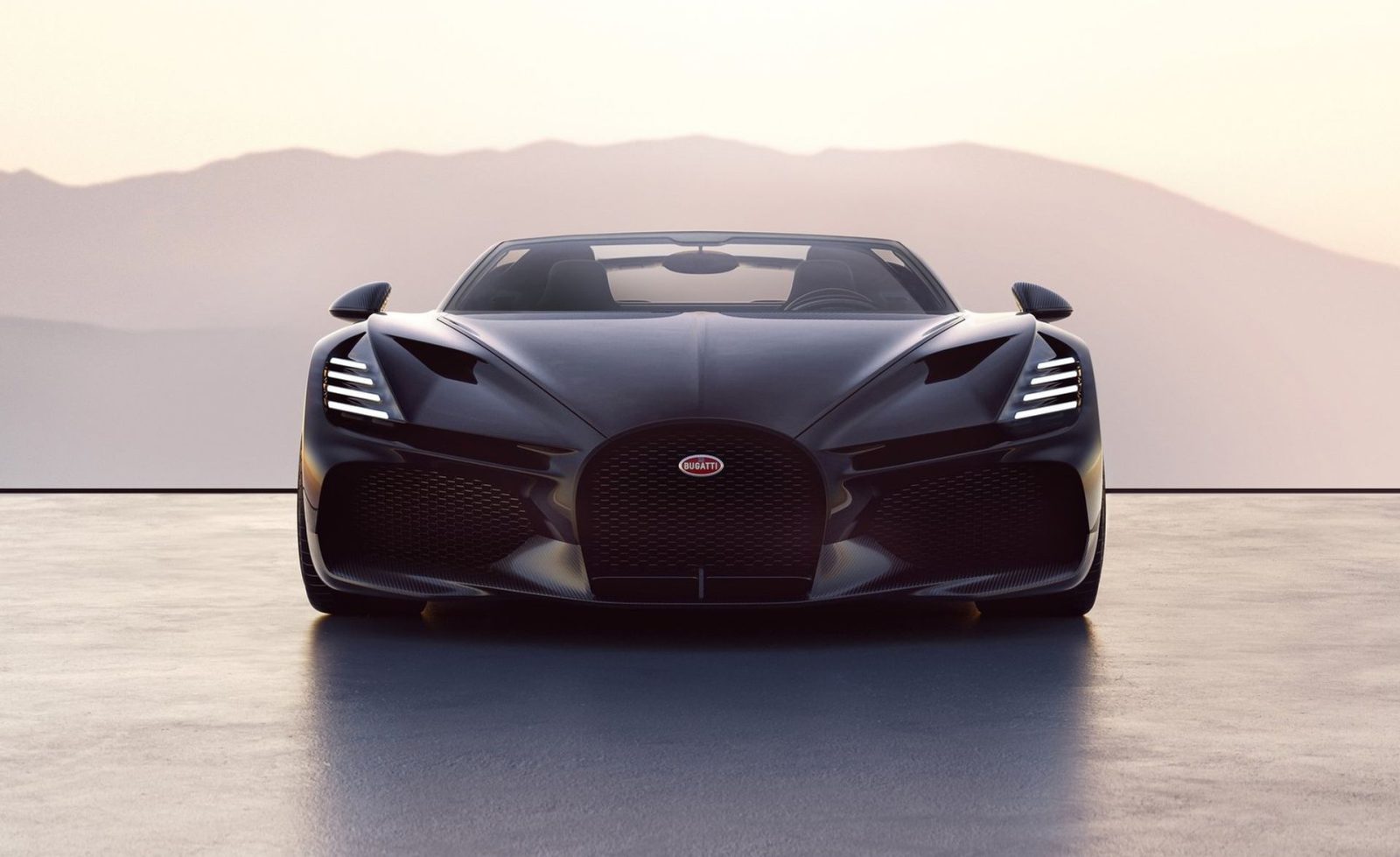 Op een gladde ondergrond staat een strakke, zwarte luxe sportwagen geparkeerd met een bergachtig landschap op de achtergrond. Met opvallende grilles en LED-koplampen is dit autojaar 2023-model het toonbeeld van modern design, mogelijk ontworpen door de beroemde ontwerper Nile van Leeuwen.