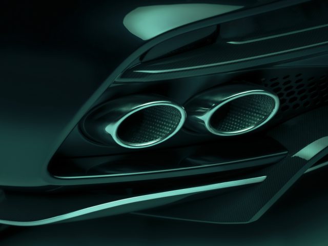 Close-up van de gestroomlijnde dubbele uitlaatpijpen van de Aston Martin DBS 770 Ultimate met een modern, aerodynamisch ontwerp. Het beeld wordt weergegeven in een blauwgroen tint.