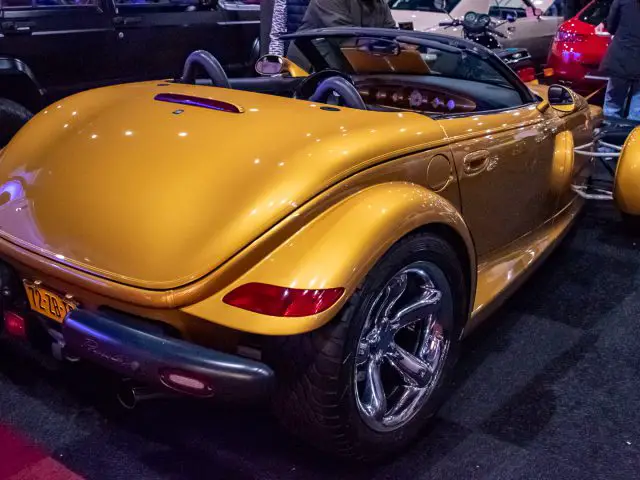 Een gouden cabriolet in vintage-stijl met opvallende spatborden en achterwielontwerp wordt prominent tentoongesteld op de indoor autoshow Interclassics Maastricht.