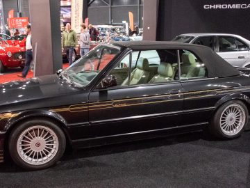 Een klassieke zwarte cabriolet met gouden details wordt tentoongesteld op de indoor autoshow van Interclassics Maastricht.