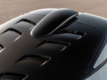 Close-up van de motorkap van de Hennessey Venom F5 Revolution Coupé met een prominente zwarte luchtinlaat en ventilatieopeningen, die de koolstofvezeldetails en vloeiende designlijnen benadrukken.