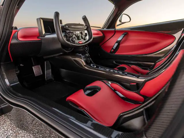 Interieur van de Hennessey Venom F5 Revolution Coupé met zwart en rood lederen stoelen, een stuur met meerdere bedieningselementen en een digitaal display op het dashboard.