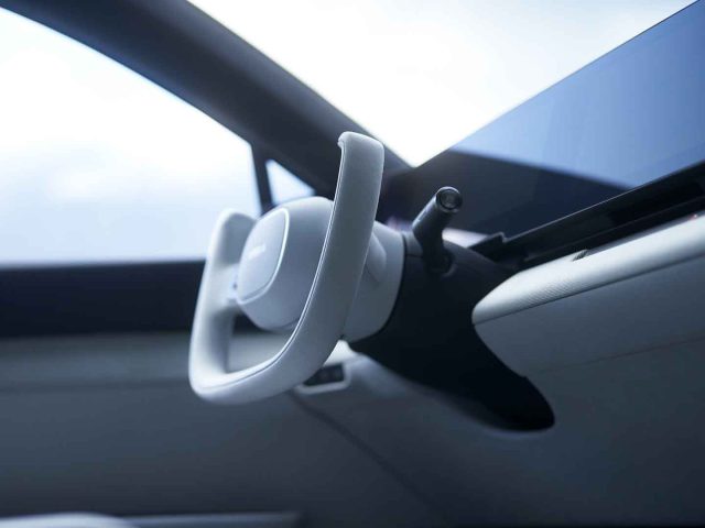 Close-up van een auto-interieur met het Afeela-stuur en een groot dashboardscherm.