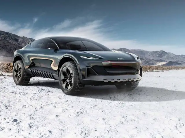 Een strakke, donkergekleurde Audi Activesphere Concept-auto staat geparkeerd op een besneeuwd terrein met bergen op de achtergrond onder een heldere hemel.