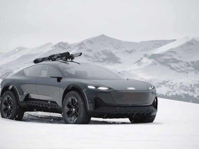 Een zwarte Audi Activesphere Concept elektrische auto met een skirek erop staat geparkeerd in een besneeuwd landschap met bergen op de achtergrond.