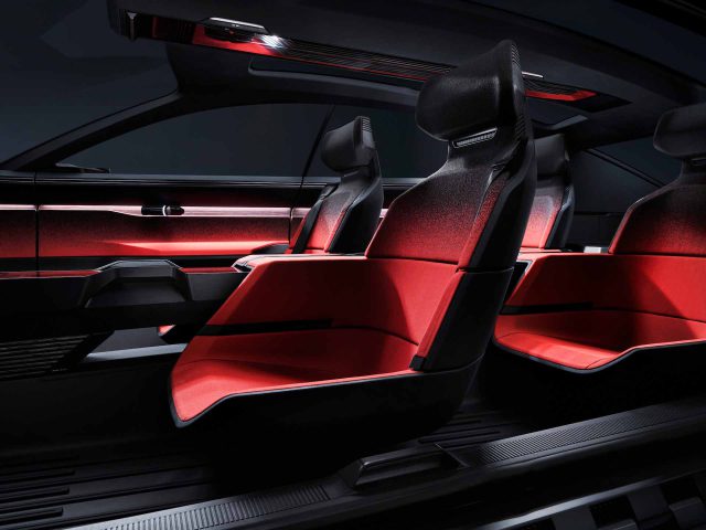 Interieur van de Audi Activesphere Concept met rode en zwarte futuristische stoelen, sfeerverlichting en een strak, minimalistisch dashboardontwerp.