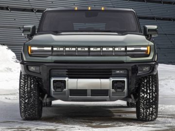 Vooraanzicht van een groene elektrische Hummer-SUV geparkeerd in de sneeuw, met een modern, hoekig ontwerp en het woord 'HUMMER' prominent op de grille weergegeven.