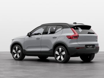 Een zilvergrijze Volvo XC40 met achterwielaandrijving staat binnen geparkeerd, gezien vanaf de passagierszijde achterin, en laat de opvallende achterlichten en het strakke ontwerp zien.