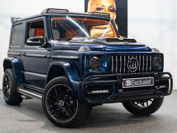 Een blauwe Brabus Jimny SUV staat binnen geparkeerd op een grijze vloer, met op de voorplaat het merk 'BB Exclusief'. Op de achtergrond is een grote advertentie met een gezicht zichtbaar.