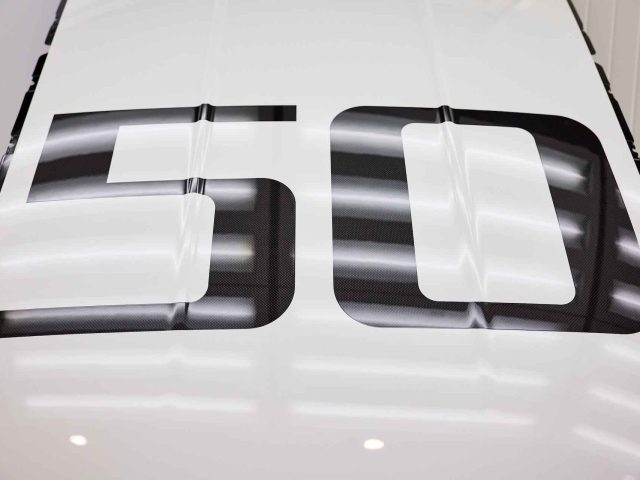 Close-up van een wit oppervlak met het nummer "50" weergegeven in een groot, krachtig zwart lettertype, dat doet denken aan het iconische BMW 3.0 CSL-ontwerp.