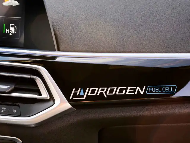 Close-up van een BMW iX5 Hydrogen-dashboard met het label "HYDROGEN FUEL CELL" nabij de ventilatieopening en een deel van het infotainmentscherm.