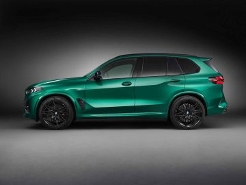 Een groene BMW X5 M Competition SUV met zwart getinte ruiten en zwarte lichtmetalen velgen wordt in profielaanzicht getoond op een effen, donkere achtergrond.