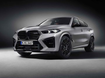 Een zilveren BMW X6 M in een studiosetting, met zijn voor- en zijprofiel met prominente grille, strak design en zwarte lichtmetalen velgen, die de felle elegantie van de BMW X5 M Competition weerspiegelen.