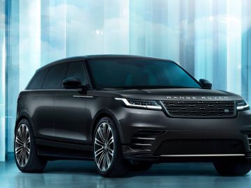Een zwarte Range Rover Velar SUV geparkeerd voor een futuristische, lichtblauwe achtergrond met reflecterende oppervlakken.