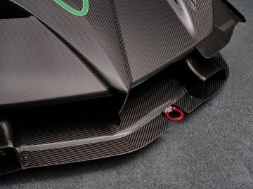 Close-up van de achterdiffusor van een Pagani Zonda R Evo met een rode trekhaak, wat het aerodynamische ontwerp en het gestructureerde koolstofvezeloppervlak benadrukt.