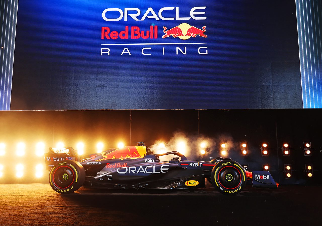 Een Formule 1-auto van Red Bull Racing wordt tentoongesteld op een podium met een groot bord "Oracle Red Bull Racing" boven het hoofd, vergezeld van felle lichten en vuurwerk, wat de opwinding van het Formule 1 seizoen 2023 benadrukt.