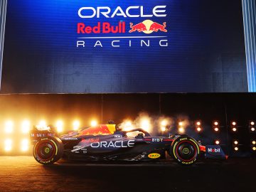 Een Formule 1-auto van Red Bull Racing wordt tentoongesteld op een podium met een groot bord "Oracle Red Bull Racing" boven het hoofd, vergezeld van felle lichten en vuurwerk, wat de opwinding van het Formule 1 seizoen 2023 benadrukt.