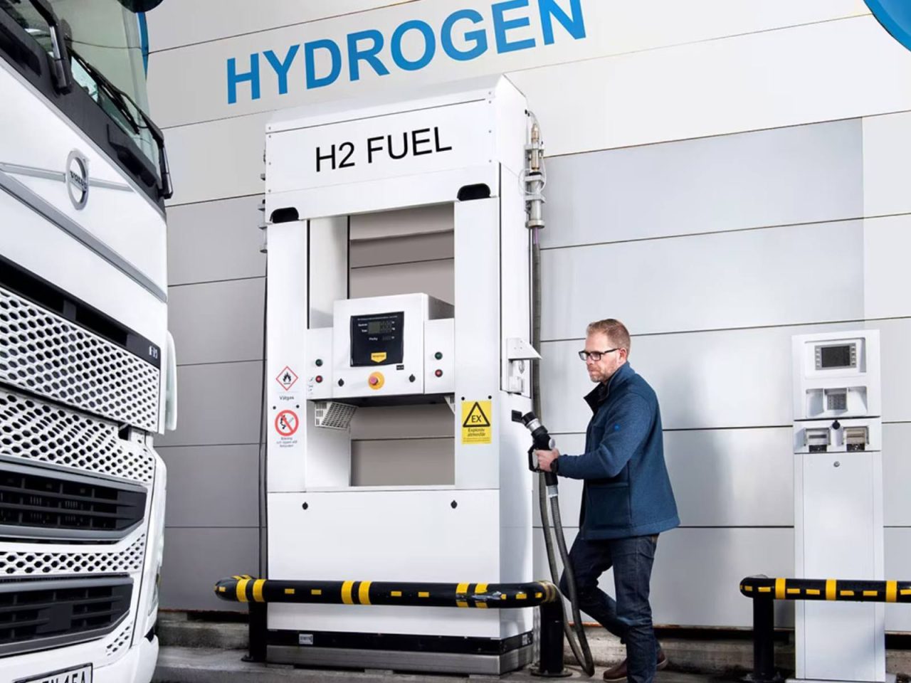 Een man tankt een vrachtwagen bij een Waterstoftankstation en zorgt ervoor dat zijn voertuig efficiënt op waterstof rijdt.