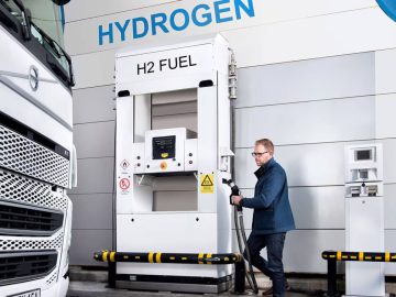 Een man tankt een vrachtwagen bij een Waterstoftankstation en zorgt ervoor dat zijn voertuig efficiënt op waterstof rijdt.