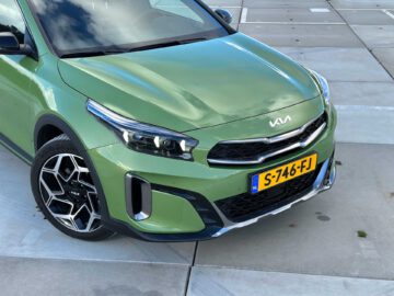 Een groene Kia XCeed, geparkeerd op een parkeerplaats met een zichtbaar kenteken met de tekst "S-746-FJ". De grille en koplampen zijn prominent aanwezig in de afbeelding.